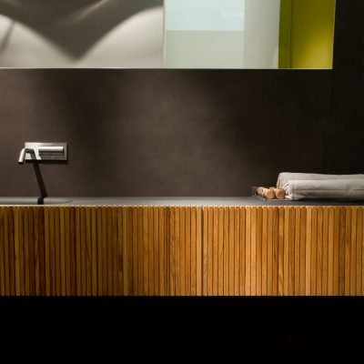 A sleek vanity with a built-in washbasin, featuring teak wood stripes on the cabinet front, complemented by stainless steel construction