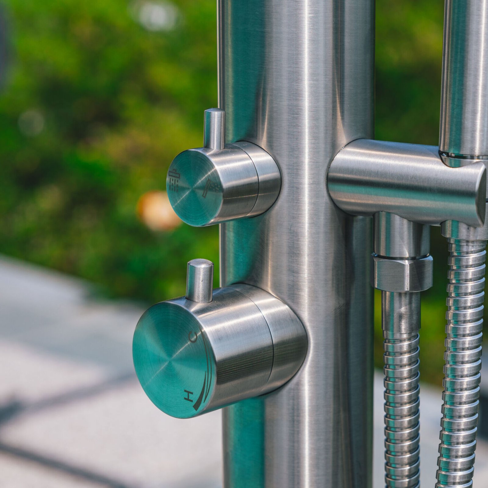 Modern freestanding outdoor shower made from marine-grade 316 stainless steel, featuring a sleek design and dual water flow control
