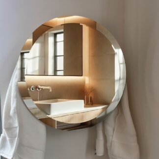 ORBEO MIRROR towel warmer radiator mounted in a contemporary bathroom setting, reflecting natural light while elegantly storing towels, blending functionality with modern style.
