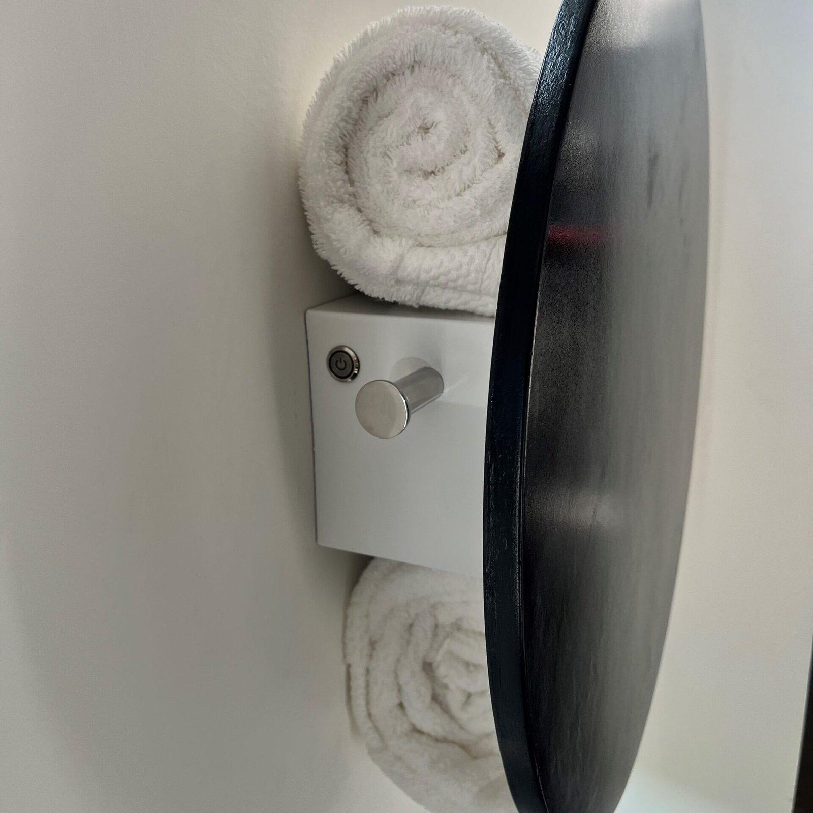 Side view of ORBEO towel warmer radiator with two integrated towel hooks and rolled towel storage space, emphasizing functional design.