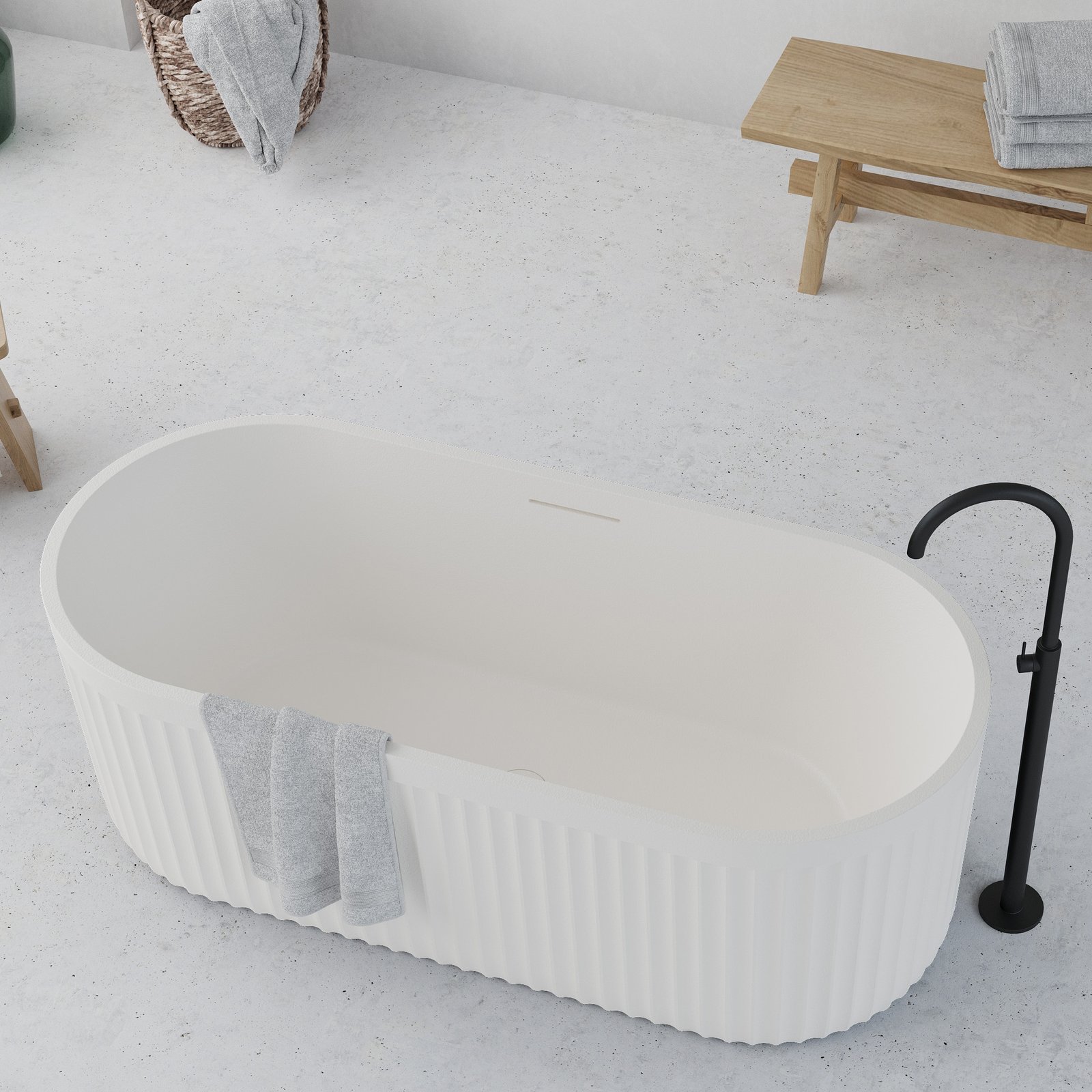 Architectural freestanding tub with matte stone-like finish and integrated overflow, designed for contemporary spaces.