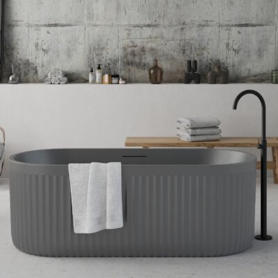 Freestanding cement grey bathtub with ribbed stone-texture exterior and modern minimalist design.