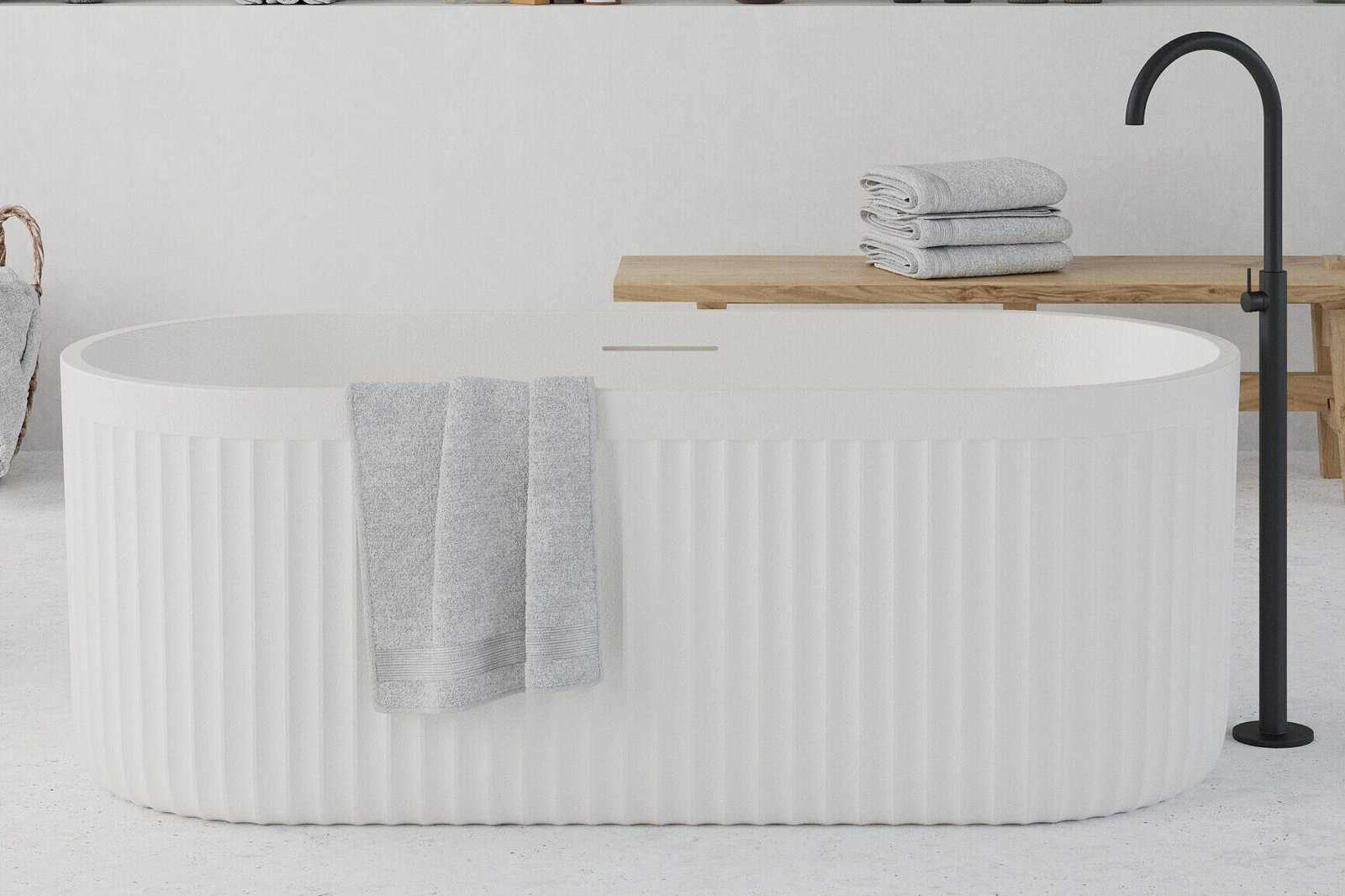 Modern white freestanding bathtub with ribbed exterior texture, placed in a minimalist bathroom interior