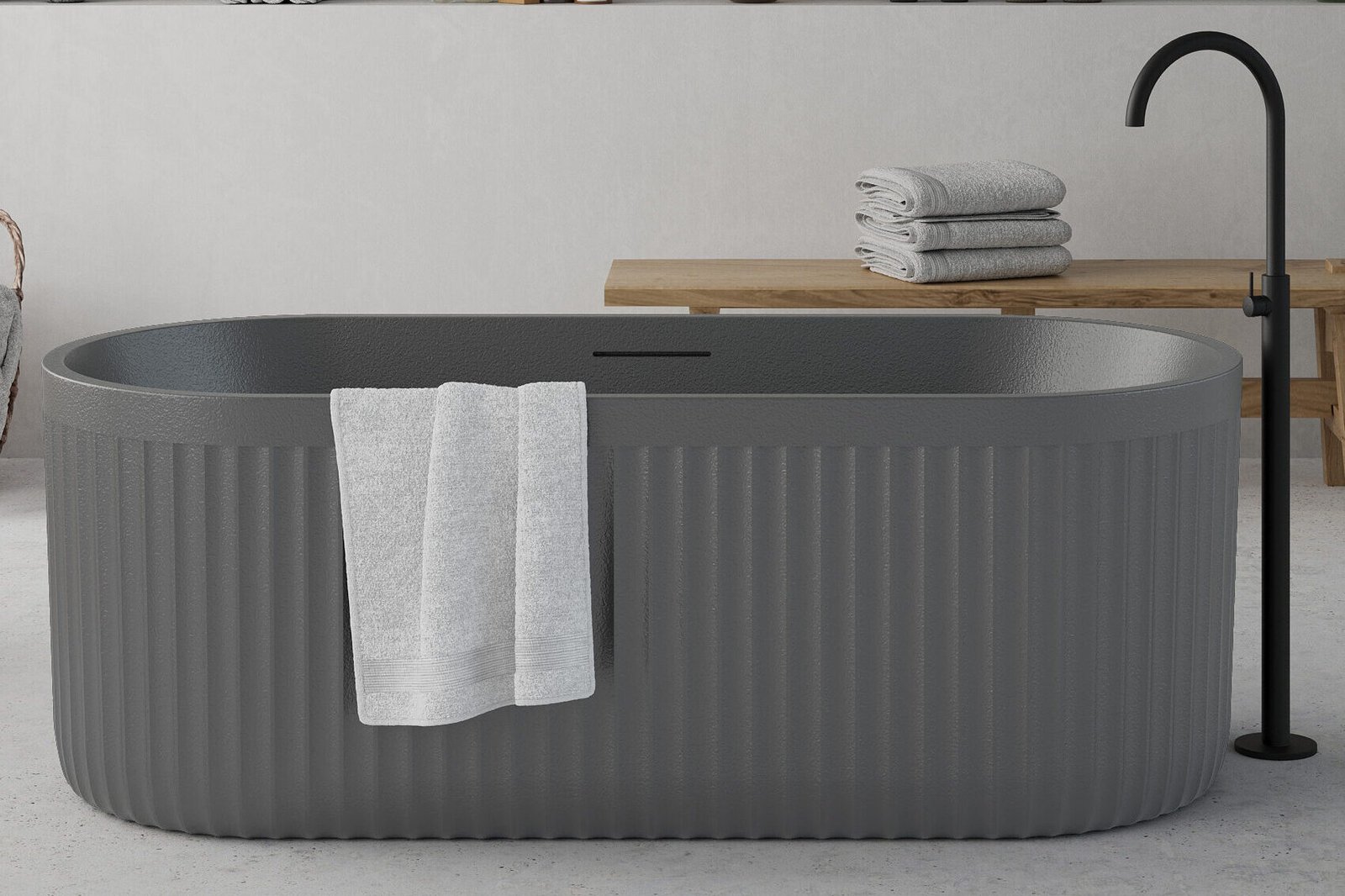 Freestanding cement grey bathtub with ribbed stone-texture exterior and modern minimalist design.